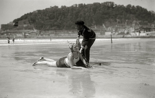 Bañero ayudando a una bañista a levantarse de la arena en San Sebastián en 1920 (Pascual Marín. CC BY-SA. Fondo Marín-Kutxa Fototeka)