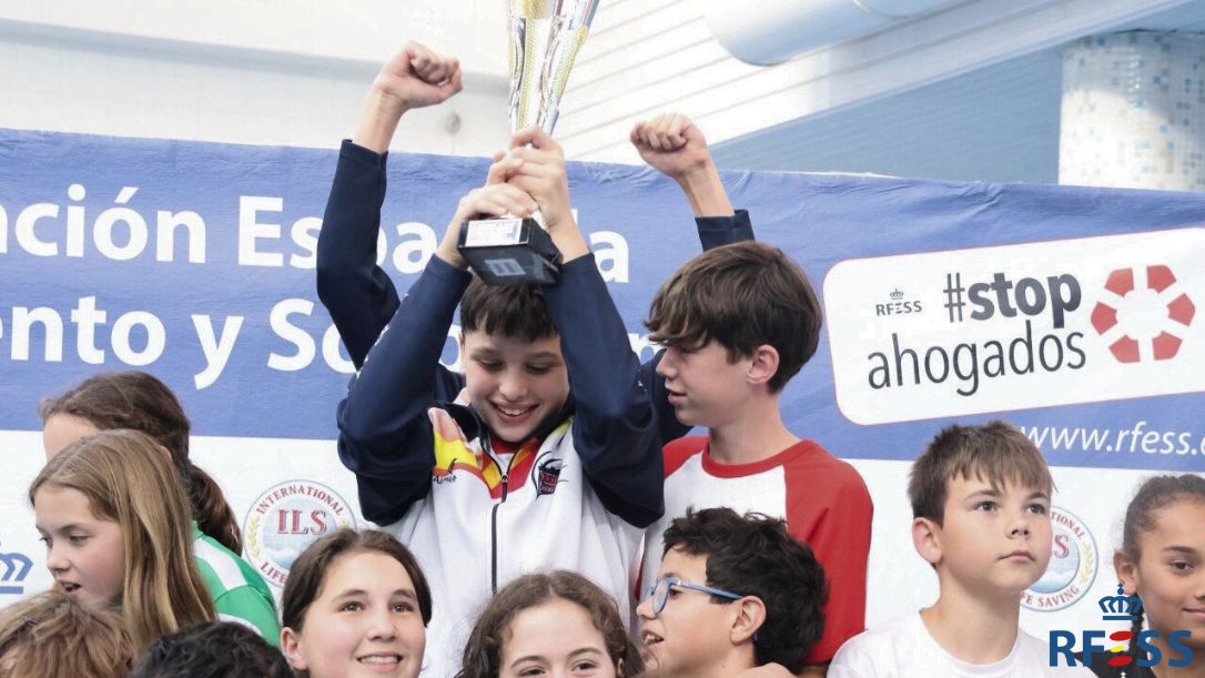 Deportistas infantiles del Club Natación Oriol Imperial celebran el primer puesto en la clasificación general de su categoría alzando el trofeo. Autor: Rosana Fuset-RFESS