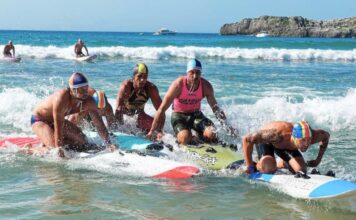 Deportistas absolutos disputan por lograr las primeras posiciones durante la carrera con tabla de salvamento en la playa de Ris, en Noja. Autora: Rosana Fuset-RFESS