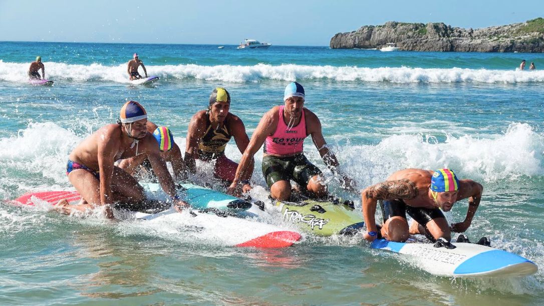 Deportistas absolutos disputan por lograr las primeras posiciones durante la carrera con tabla de salvamento en la playa de Ris, en Noja. Autora: Rosana Fuset-RFESS