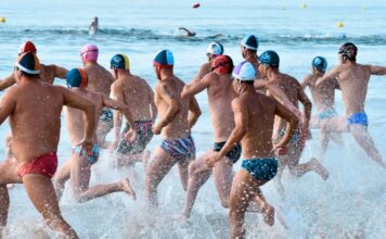 Socorristas masculinos se adentran en el agua para afrontar la prueba de nadar surf en la Playa del Gurugú de Castelló durante la última edición del Campeonato de España de Verano en 2024. Autor: Javier Sánchez-RFESS