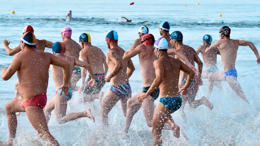 Socorristas masculinos se adentran en el agua para afrontar la prueba de nadar surf en la Playa del Gurugú de Castelló durante la última edición del Campeonato de España de Verano en 2024. Autor: Javier Sánchez-RFESS